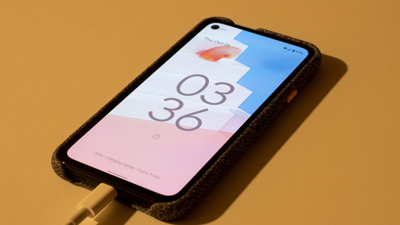 smartphone running android 12, showing the lockscreen while charging on a yellow table