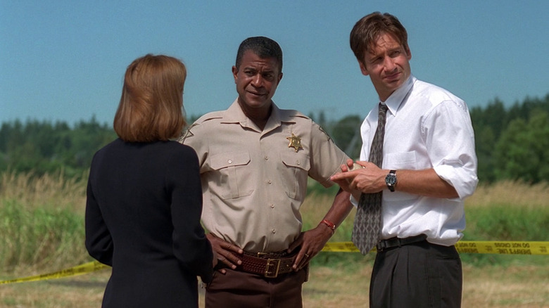 Scully, Sheriff Taylor, and Mulder standing on a field in The X-Files episode Home