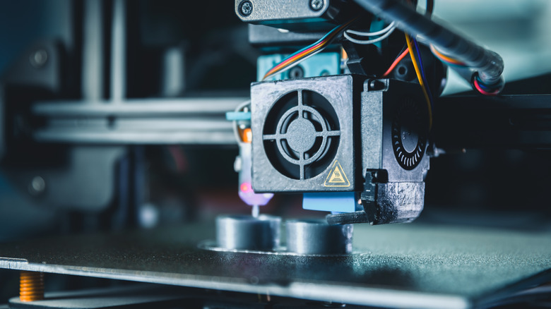 Close up of a 3D printer extruder layering filament to create an object.
