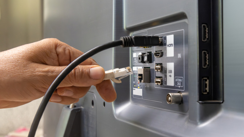 A person plugging in an Ethernet cable into a TV