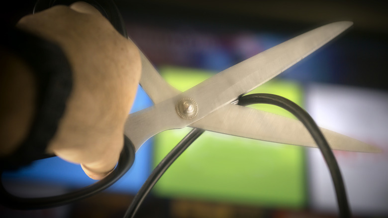 A person using a pair of scissors to cut a wire.