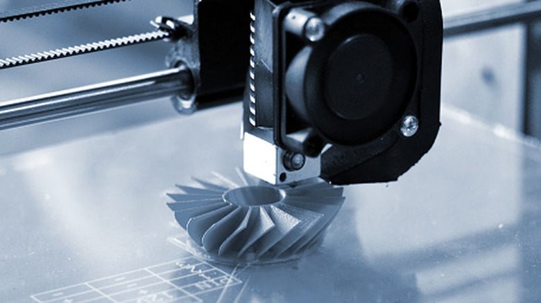 Close up of a 3D printer extruder releasing filament for a project.