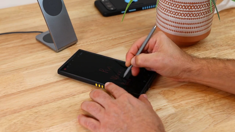 A person using the Samsung S Pen to write on a phone with a MagBak case