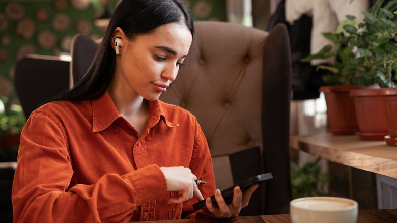 A person wearing AirPods and interacting with an iPhone