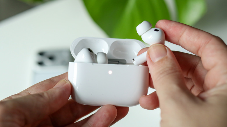 A hand removing an AirPod from the case