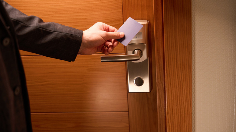 A person trying to unlock a hotel door with a keycard.