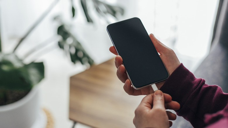 a person plugging in a white usb-c into a smartphone