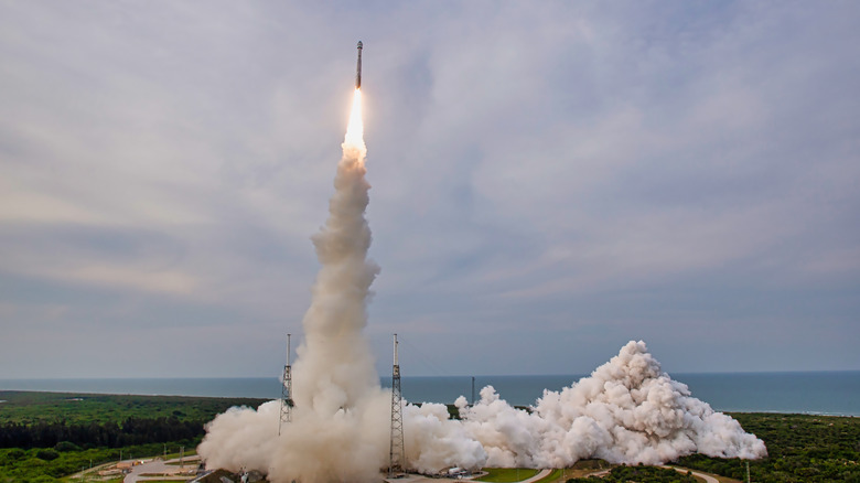 wide view of rocket lifting off from launchpad with smoke billowing out