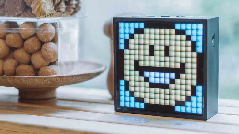 The Divoom TimeBox Evo Pixel Art Bluetooth Speaker sitting on a windowsill next to some decorative objects sitting in a bowl