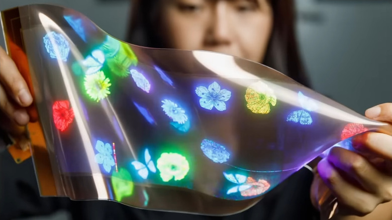 A woman stretching and twisting a stretchable display panel.