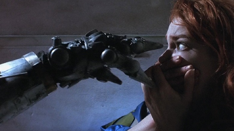 Jill covering her mouth while a robotic hand is reaching toward her