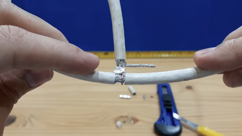 A person hooking the exposed center conductor of coaxial to a section of exposed copper shielding.