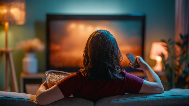 Person with remote and popcorn watching TV