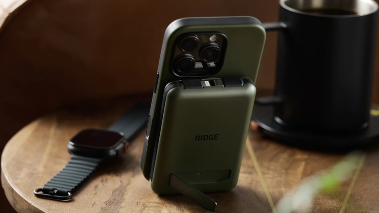 An olive MagSafe power bank with a stand charging a matching iPhone.