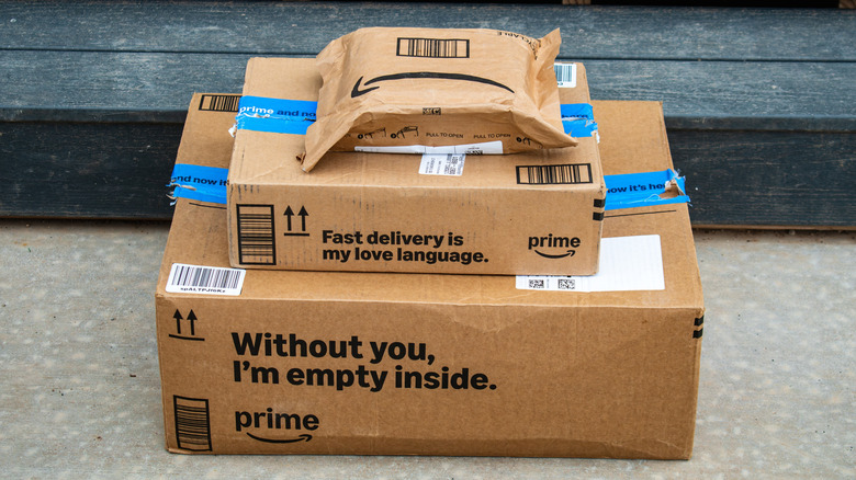 A neat stack of three Amazon packages sitting outside in front of some steps, each one smaller than the previous, with the pile resembling something like a pyramid