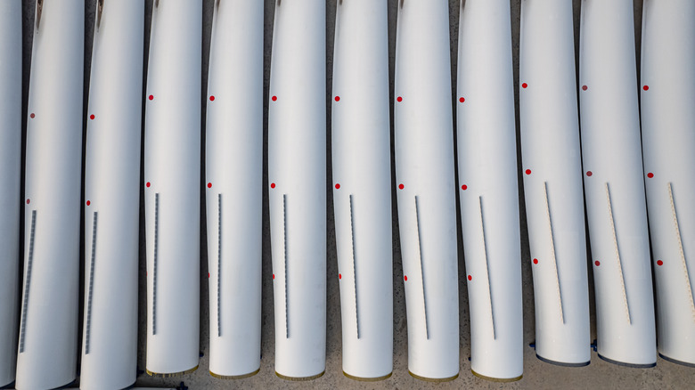 Numerous wind-turbine blades lined up side by side in storage.