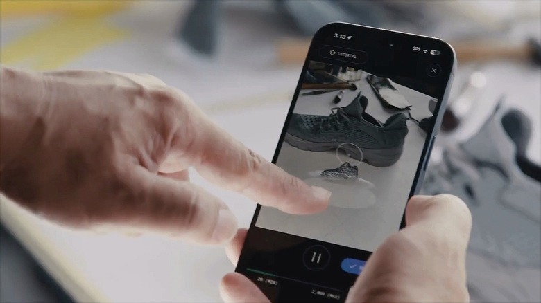 A hand tapping a phone scanning a black shoe using the Polycam app.