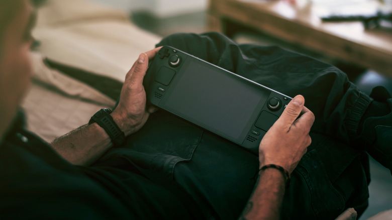 A person holding a Steam Deck while sitting on a sofa