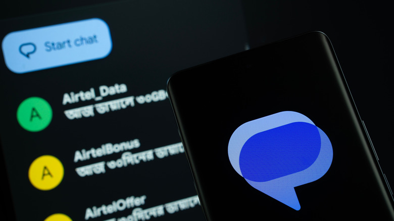 The Google Messages symbol displayed on a smartphone screen in front of a digital contact list