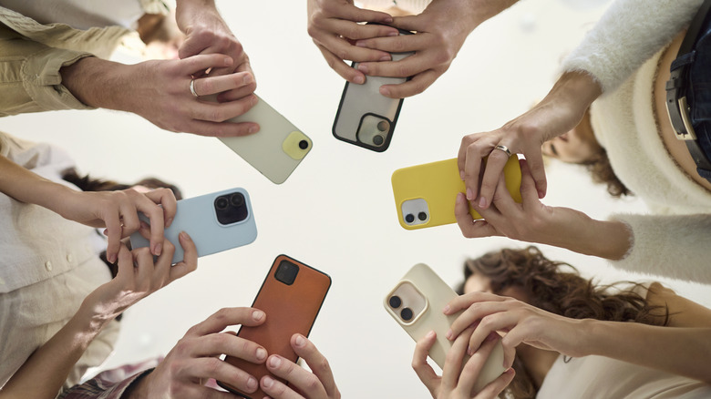 Various people standing in a circle and setting up a smartphone group chat