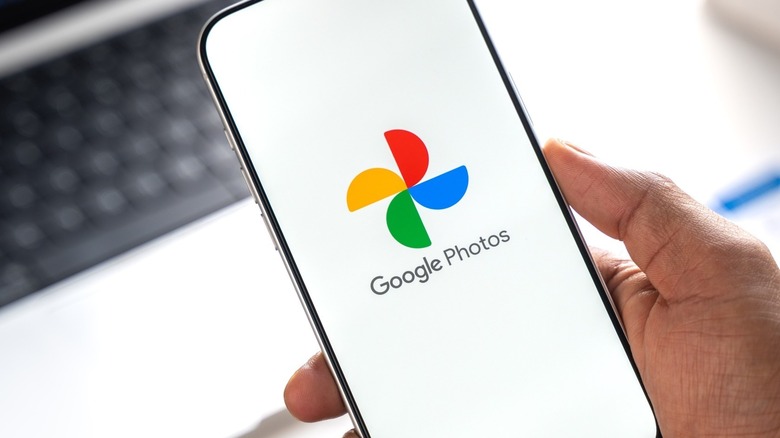 Google Photos app logo on smartphone display in office setting.
