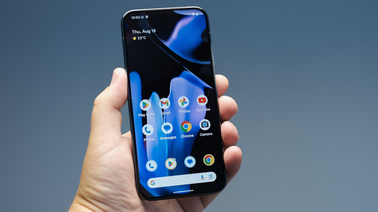 a person holding a google pixel 9 showing the home screen