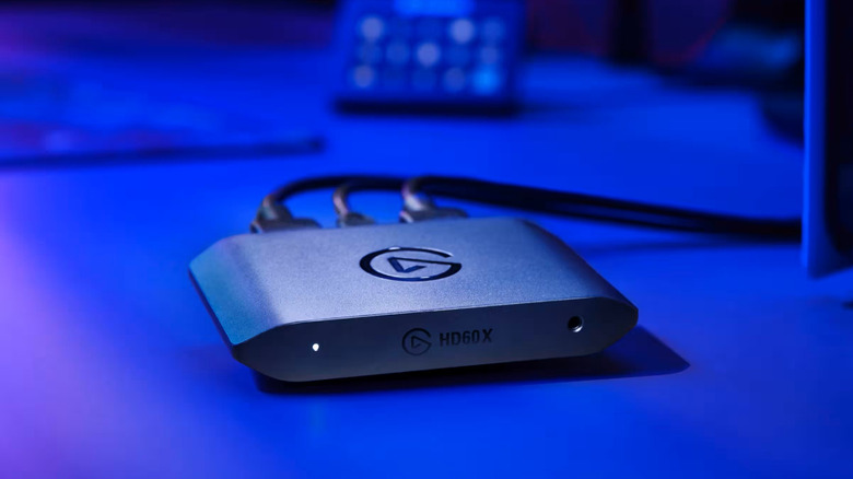 Elgato HD60 X external capture card on desk by PC monitors and PS5.