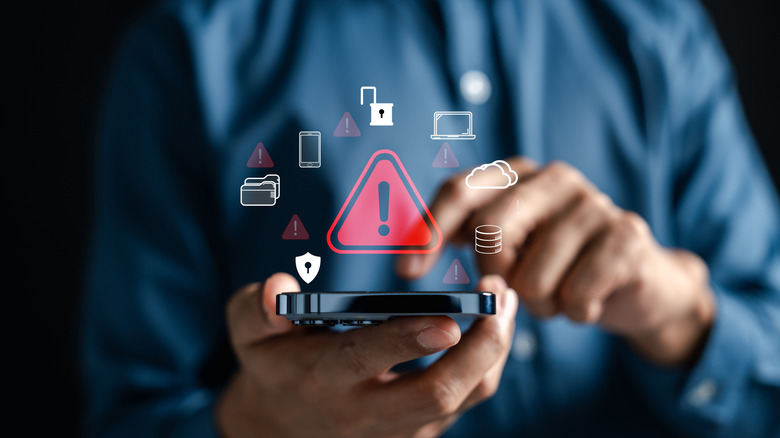 Person using smartphone with virtual warning symbol shown above.