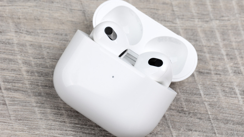 The AirPods Pro 3, in charging case, laid on a wooden surface.
