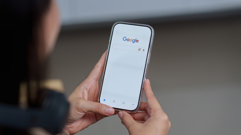 Hands holding iPhone while searching on Google