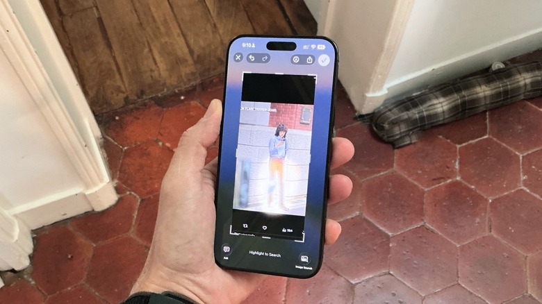 Hand holding an iPhone 16 Pro Max, using Visual Intelligence feature on a screenshot