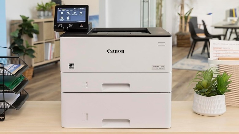 Canon imageClass LBP247dw printer resting atop a table in an office.