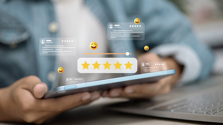 An individual holding what appears to be a iPad tablet in between both of their hands, above the tablet is computer generated graphics representing customer reviews and 5-star ratings