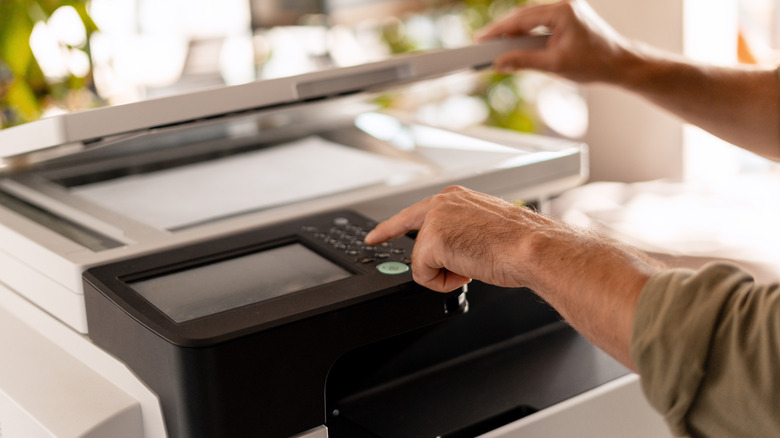 Person using a multifunction printer's control panel while scanning a document.