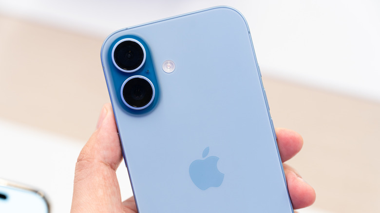 Hand holding a new iPhone 17 Mist Blue in a Store.