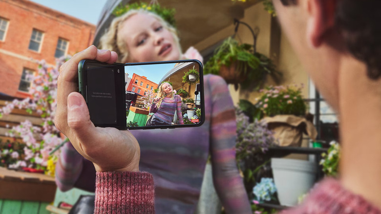 Person holding Motorola Razr folded 90 degrees out to take image with half the screen