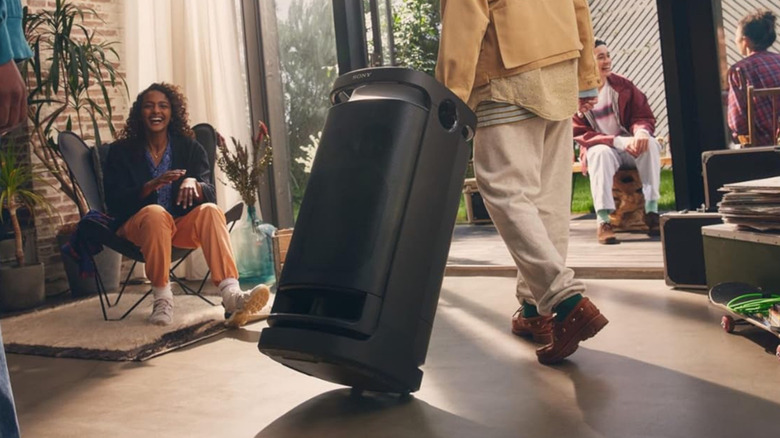 A person wheeling the Sony SRS-XV900 speaker inside a home packed with party guests.