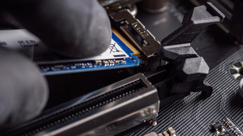 Close-up of someone installing an NVMe solid-state drive into a motherboard slot.