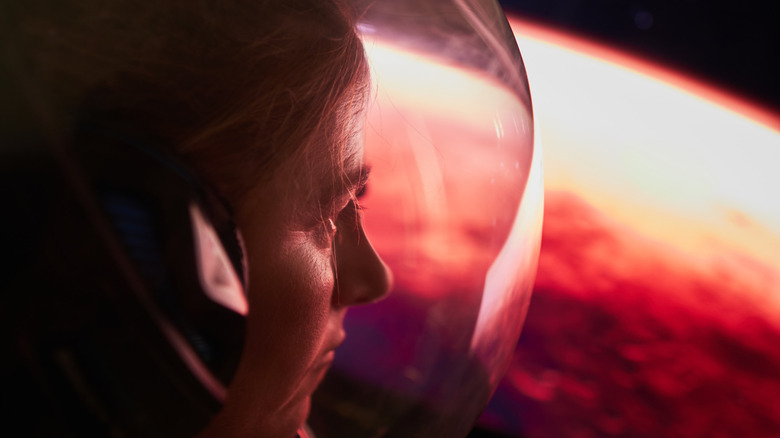 female astronaut looking down at Mars through her space helmet