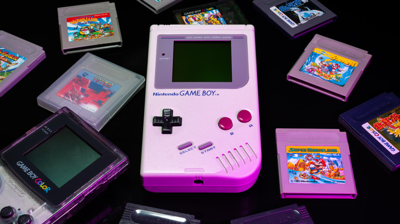Original Game Boy and Game Boy Color, surrounded by games cartridges on a black background