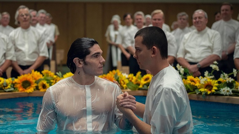Asa Butterfield holding Fra Fee's hand as they stand in a pool of waste-deep water, both are wearing white shirts, though it is apparent that Fee was submerged