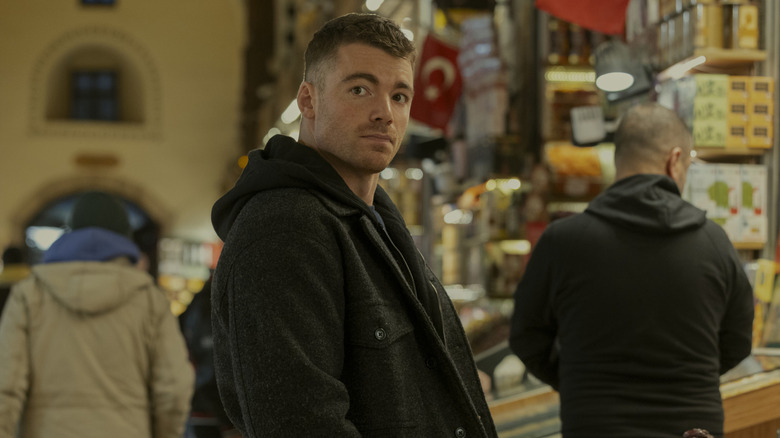 Peter Sutherland (Gabriel Basso) stood in a market in The Night Agent