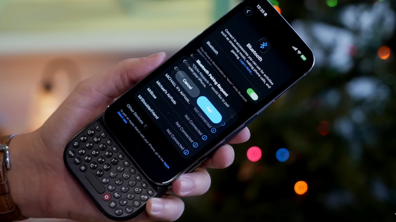 Man holding Clicks Power Keyboard connecting to phone via Bluetooth