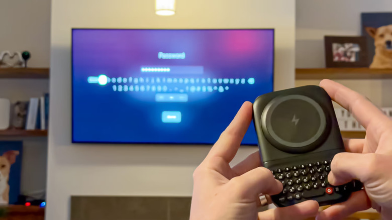 Hand holding detached Clicks Power Keyboard to control smart TV