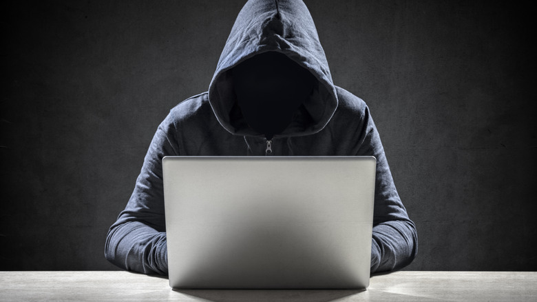 A man in a hood at a laptop