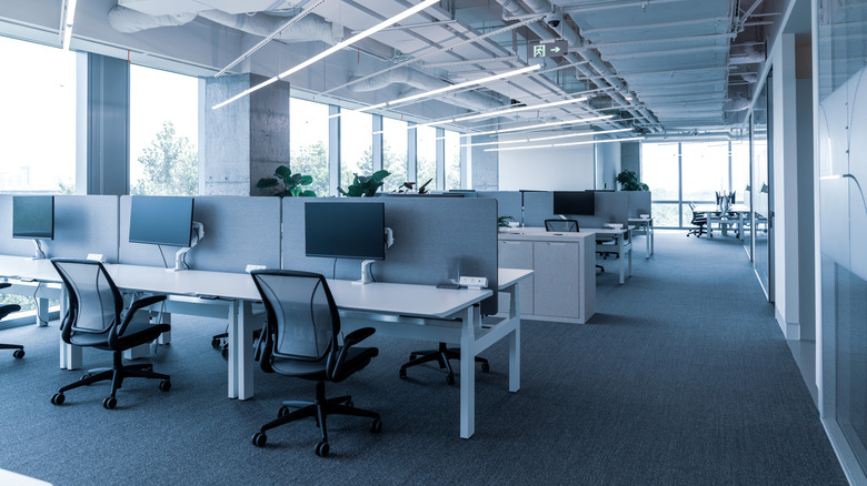 Modern open office floor plan with lots of computer monitors and desks visible.