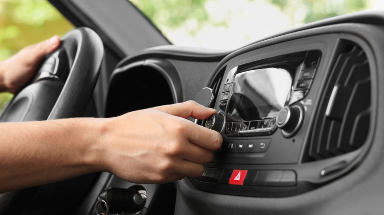 A person rotating the volume dial in their car's infotainment system