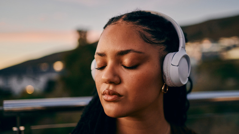 A woman with her eyes closed, listening to music with headphones on
