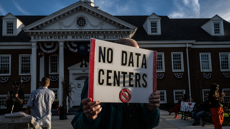 A protester holding a "No data centers" sign in front of the Kenilworth Municipal Building in Kenilworth, NJ