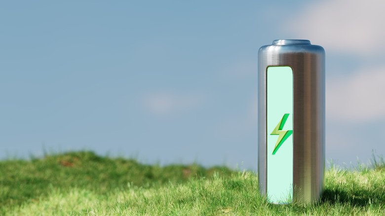 green energy concept, battery resting on green grassy hill